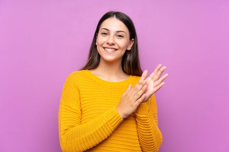 Young woman over isolated purple background applauding