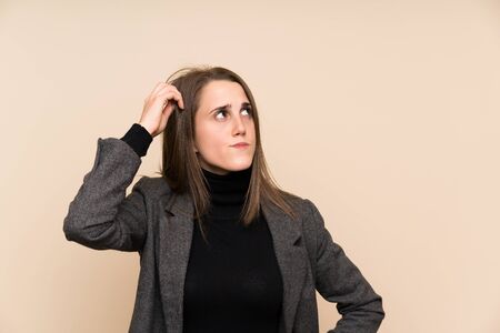 Young woman over isolated wall having doubts and with confuse face expressionの写真素材