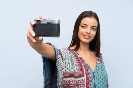 Young woman over isolated blue wall making a selfie