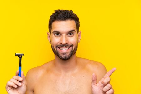 Man shaving his beard surprised and pointing finger to the sideの写真素材