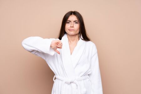 Young girl in a bathrobe over isolated background showing thumb down signの写真素材