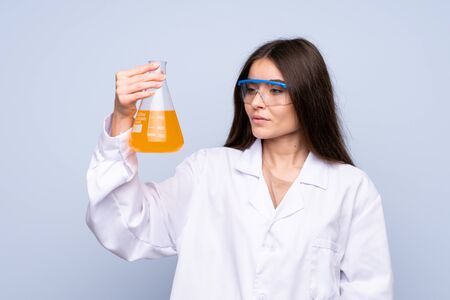 Young woman over isolated blue background with a scientific test tubeの写真素材