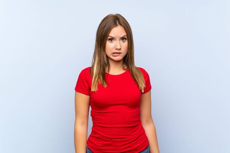Teenager girl over isolated blue background having doubts and with confuse face expressionの写真素材