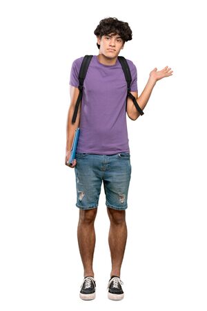 A full-length shot of a Young student man having doubts while raising hands over isolated white backgroundの写真素材