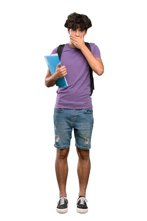 A full-length shot of a Young student man covering mouth with hands over isolated white backgroundの写真素材