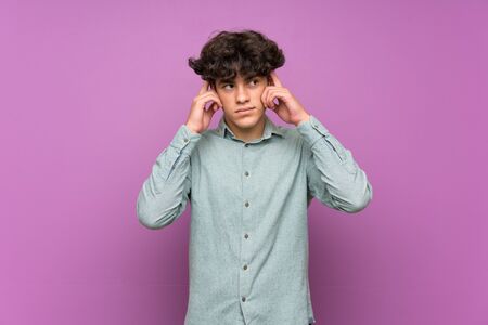 Young man over isolated purple wall having doubts and thinkingの写真素材