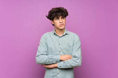 Young man over isolated purple wall with confuse face expressionの写真素材