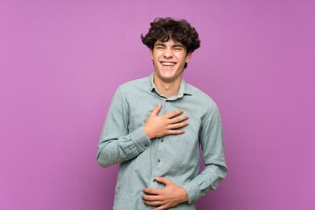 Young man over isolated purple wall smiling a lotの写真素材