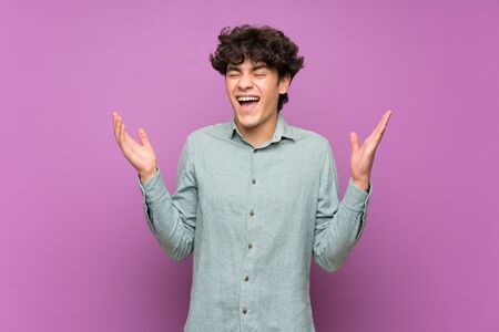 Young man over isolated purple wall smiling a lotの写真素材