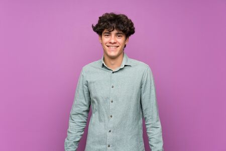 Young man over isolated purple wall smiling a lotの写真素材