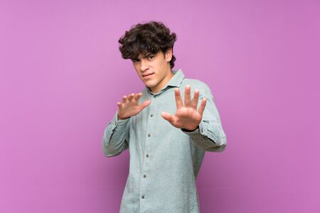 Young man over isolated purple wall nervous stretching hands to the frontの写真素材