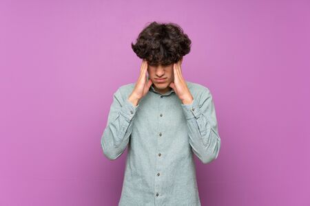 Young man over isolated purple wall with headacheの写真素材