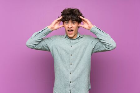 Young man over isolated purple wall with surprise expressionの写真素材