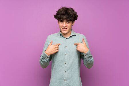 Young man over isolated purple wall with surprise facial expressionの写真素材