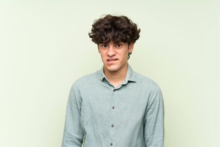 Young man over isolated green wall having doubts and with confuse face expressionの写真素材