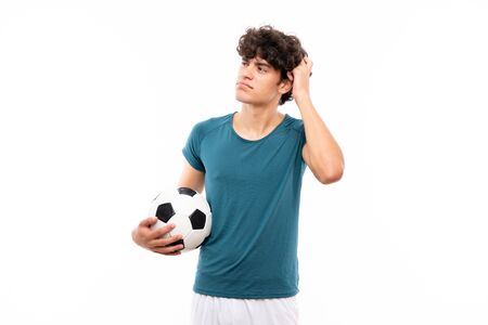 Young football player man over isolated white wall having doubts and with confuse face expressionの写真素材