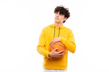 Young basketball player man over isolated white wall looking up while smilingの写真素材