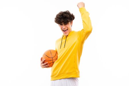 Young basketball player man over isolated white wall celebrating a victory