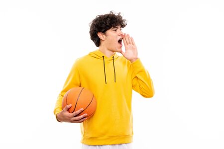 Young basketball player man over isolated white wall shouting with mouth wide openの写真素材