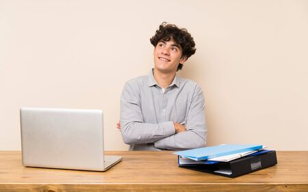 Young student man with a laptop looking up while smilingの写真素材