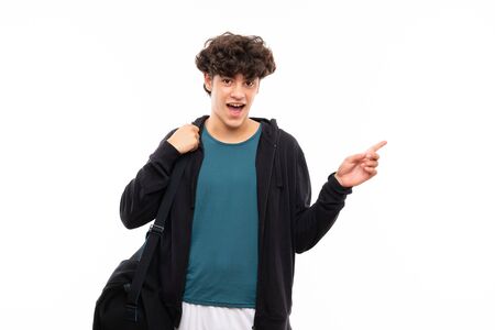 Sport man over isolated white background surprised and pointing finger to the sideの写真素材