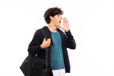 Sport man over isolated white background shouting with mouth wide openの写真素材