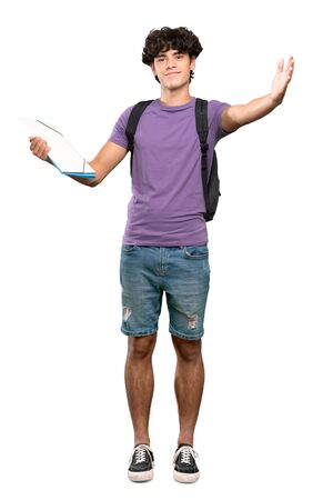 A full-length shot of a Young student man presenting and inviting to come with hand over isolated white backgroundの写真素材