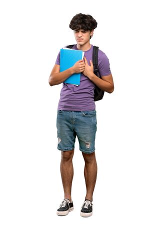 A full-length shot of a Young student man having a pain in the heart over isolated white backgroundの写真素材