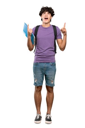 A full-length shot of a Young student man surprised and pointing up over isolated white backgroundの写真素材
