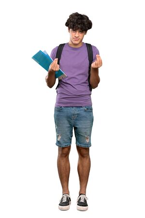 A full-length shot of a Young student man making money gesture over isolated white backgroundの写真素材