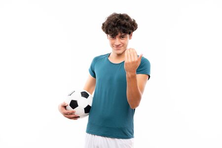 Young football player man over isolated white wall inviting to come with hand. Happy that you cameの写真素材