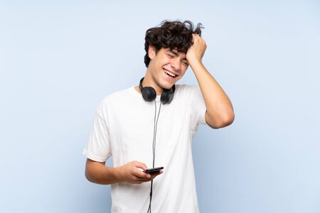 Young man listening music with a mobile over isolated blue wall has realized something and intending the solutionの写真素材