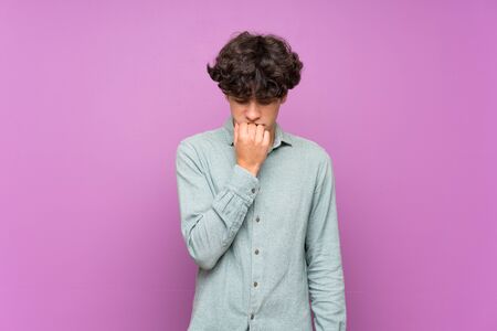 Young man over isolated purple wall having doubtsの写真素材