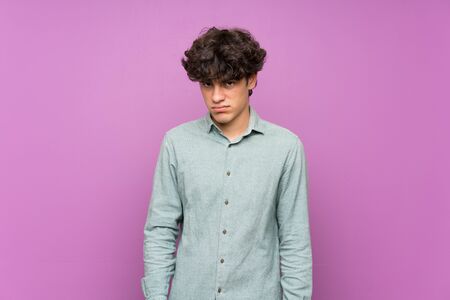 Young man over isolated purple wall with sad and depressed expressionの写真素材