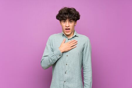 Young man over isolated purple wall surprised and shocked while looking rightの写真素材
