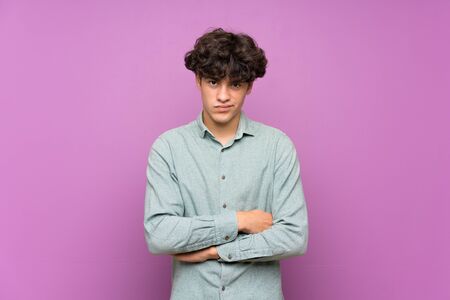 Young man over isolated purple wall feeling upsetの写真素材