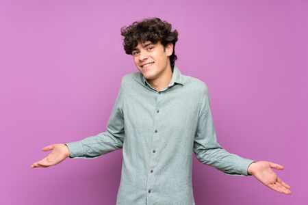 Young man over isolated purple wall smilingの写真素材