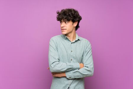 Young man over isolated purple wall portraitの写真素材