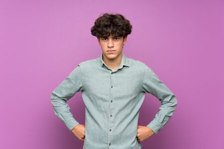Young man over isolated purple wall angryの写真素材
