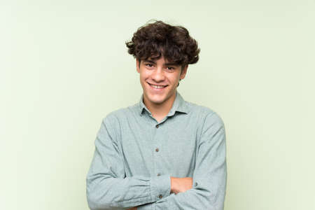 Young man over isolated green wall laughingの写真素材