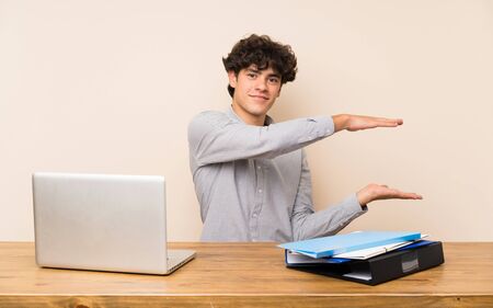 Young student man with a laptop holding copyspace to insert an adの写真素材