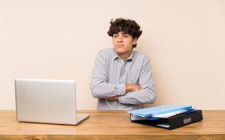 Young student man with a laptop making doubts gesture while lifting the shouldersの写真素材