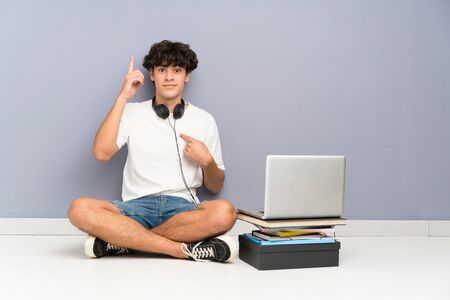 Young man with his laptop sitting one the floor with surprise facial expressionの写真素材
