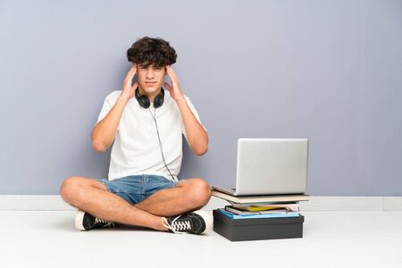 Young man with his laptop sitting one the floor unhappy and frustrated with something. Negative facial expressionの写真素材