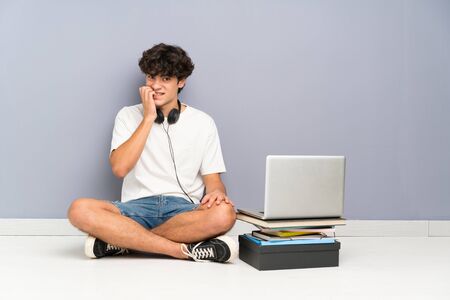 Young man with his laptop sitting one the floor nervous and scaredの写真素材