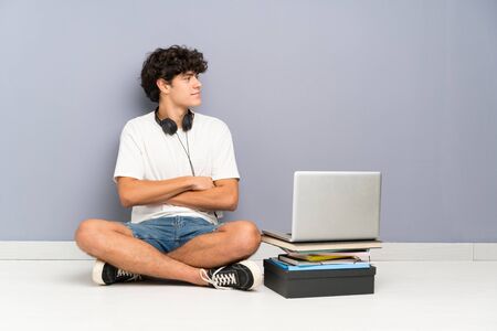 Young man with his laptop sitting one the floor looking to the sideの写真素材