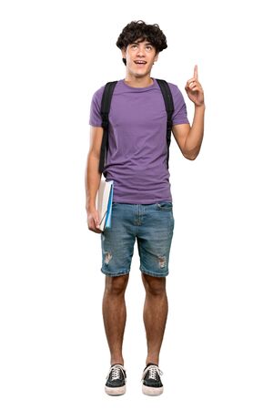 A full-length shot of a Young student man pointing up and surprised over isolated white backgroundの写真素材