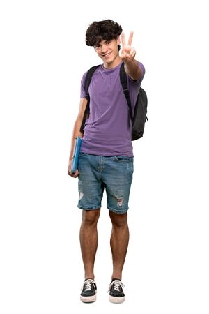A full-length shot of a Young student man smiling and showing victory sign over isolated white backgroundの写真素材