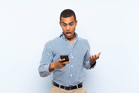 Young handsome brunette man over isolated blue background surprised and sending a messageの写真素材