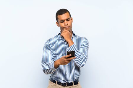 Young handsome brunette man over isolated blue background thinking and sending a messageの写真素材